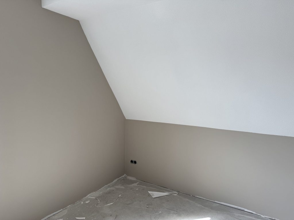 Zolderkamer met een witte schuine kap boven zandkleurig gesausde vlieswanden